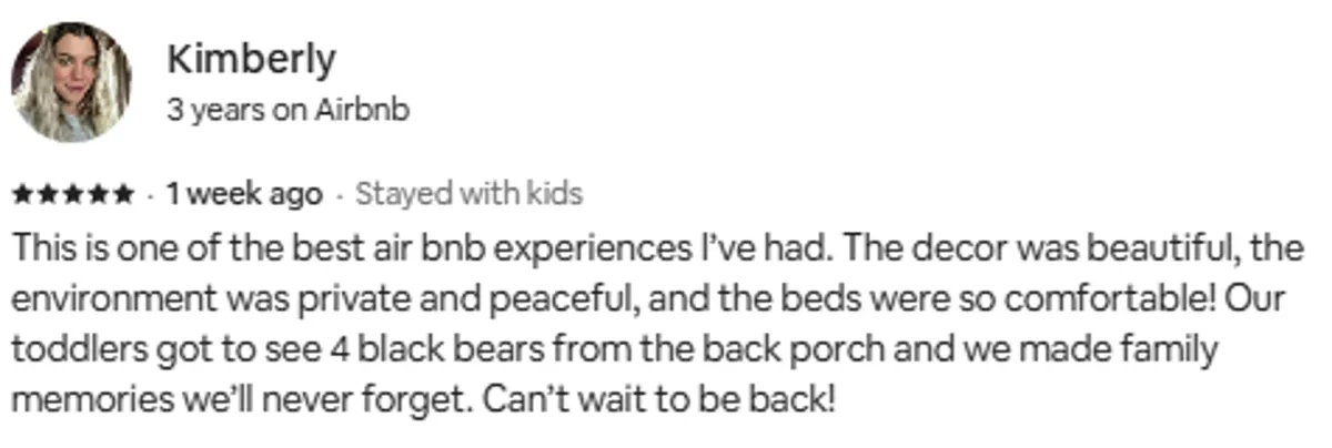 A warm, inviting bedroom with comfortable beds, beautiful mountain-inspired décor, and a glimpse of a peaceful back porch through the window. The setting suggests a place for relaxation, wildlife watching, and gathering with loved ones, blending indoor comfort with natural surroundings.