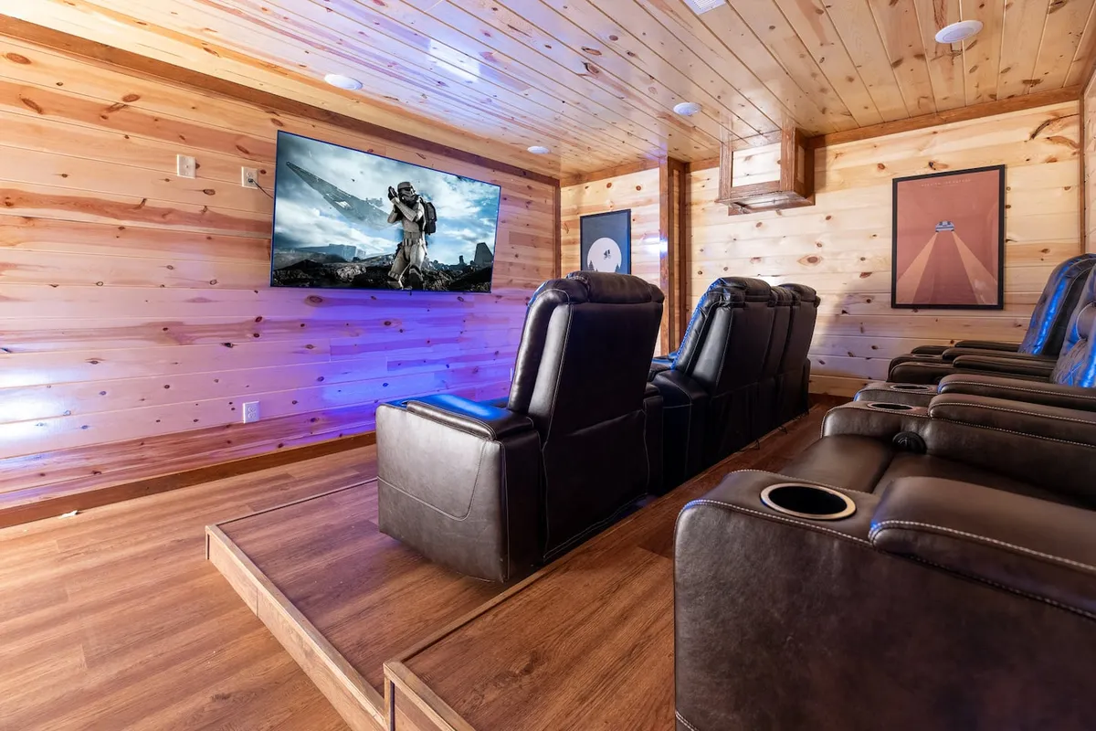 A comfortable, dedicated theater room with reclining seats, a large television screen, and wood paneling, all arranged to create a cinematic atmosphere ideal for group movie nights.